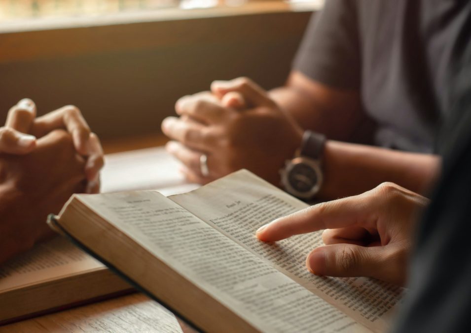 young man reading bible with friends who are praying to God Join the cell group at the church.